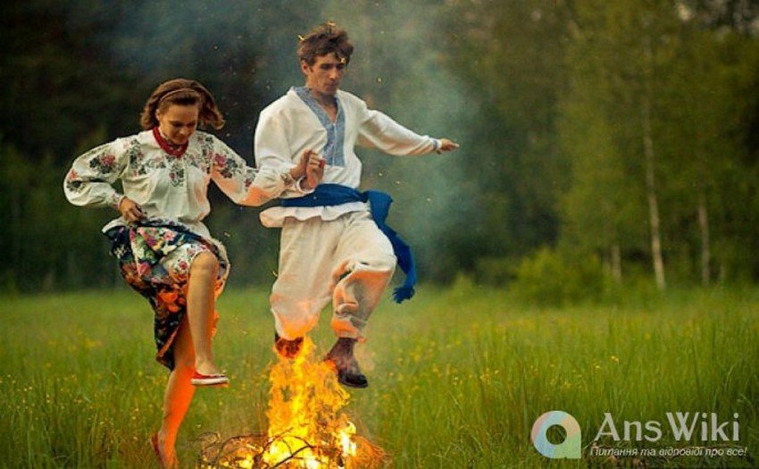 Дівчина і хлопець стрибають через багаття